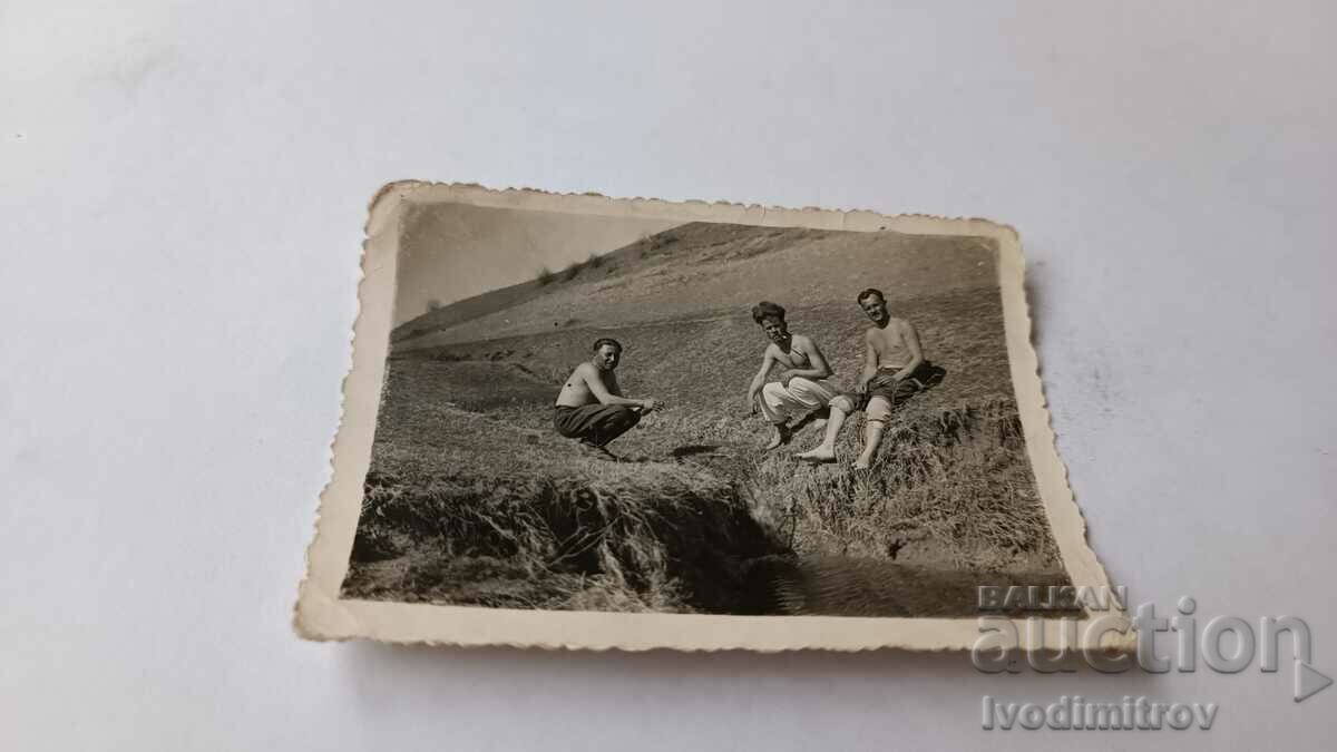 Photo Three men naked to the waist by an irrigation canal