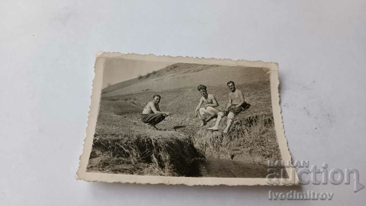 Foto Trei bărbați goi până la brâu lângă un canal de irigare