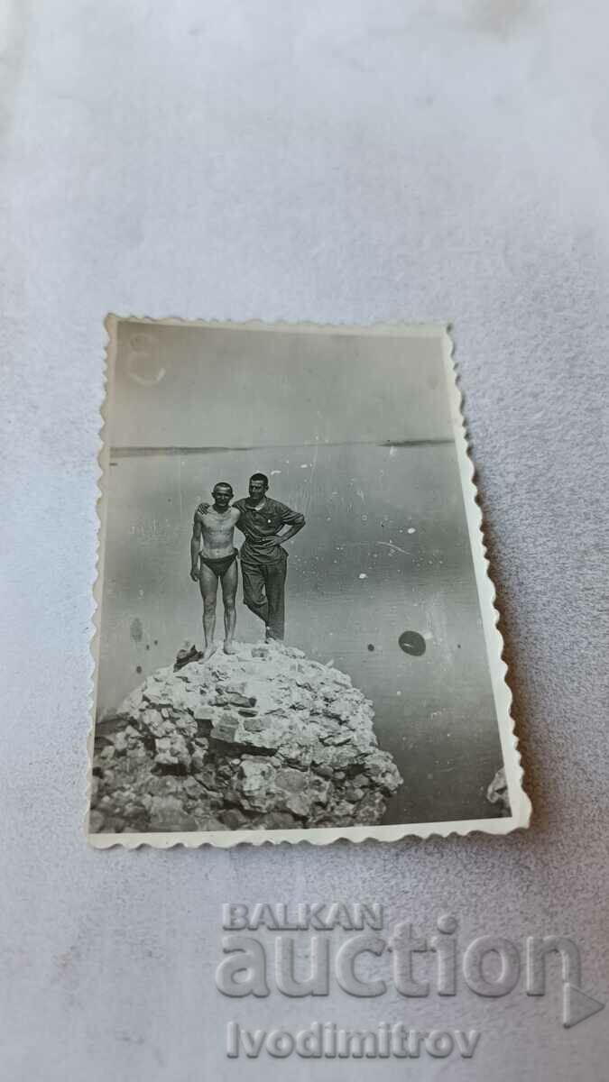 Foto Doi bărbați pe o stâncă deasupra mării