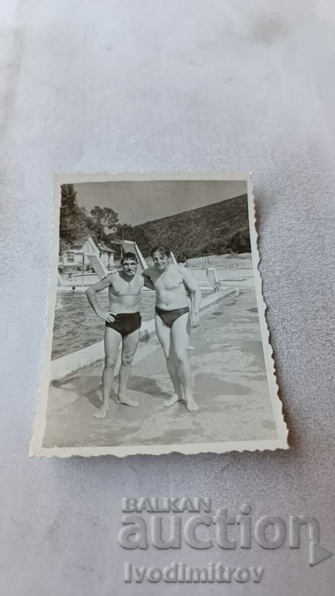 Photo Two young men in swimsuits by a pool