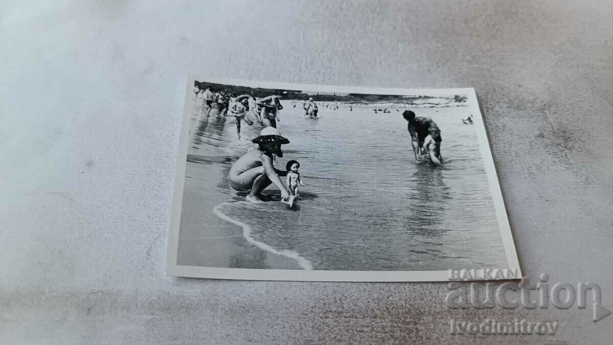 Fotografie Fetiță cu o păpușă pe plajă