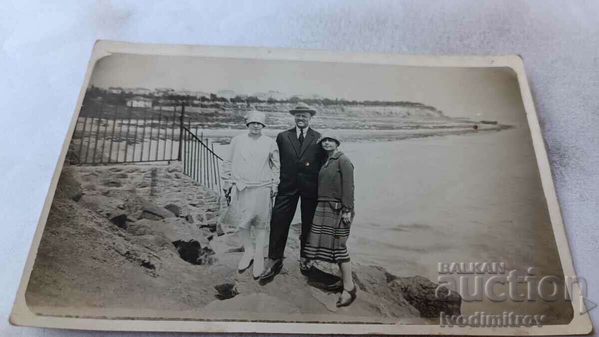 Photo A man and two women on a cliff above the sea