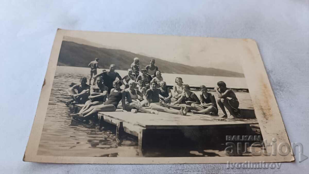 Photo Men women and children on a wooden platform in a lake