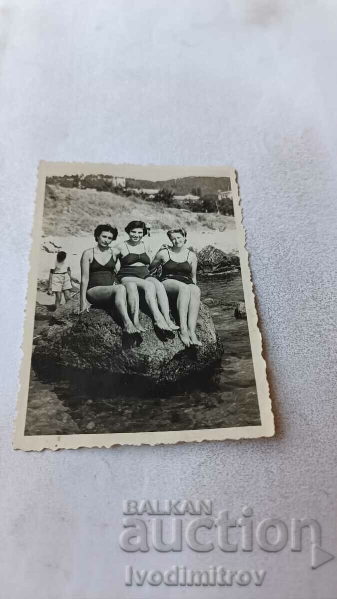 Photo Three young girls on a stone on the seashore