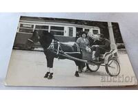 Photo A man and three women with a two-wheeled donkey in front of a tram