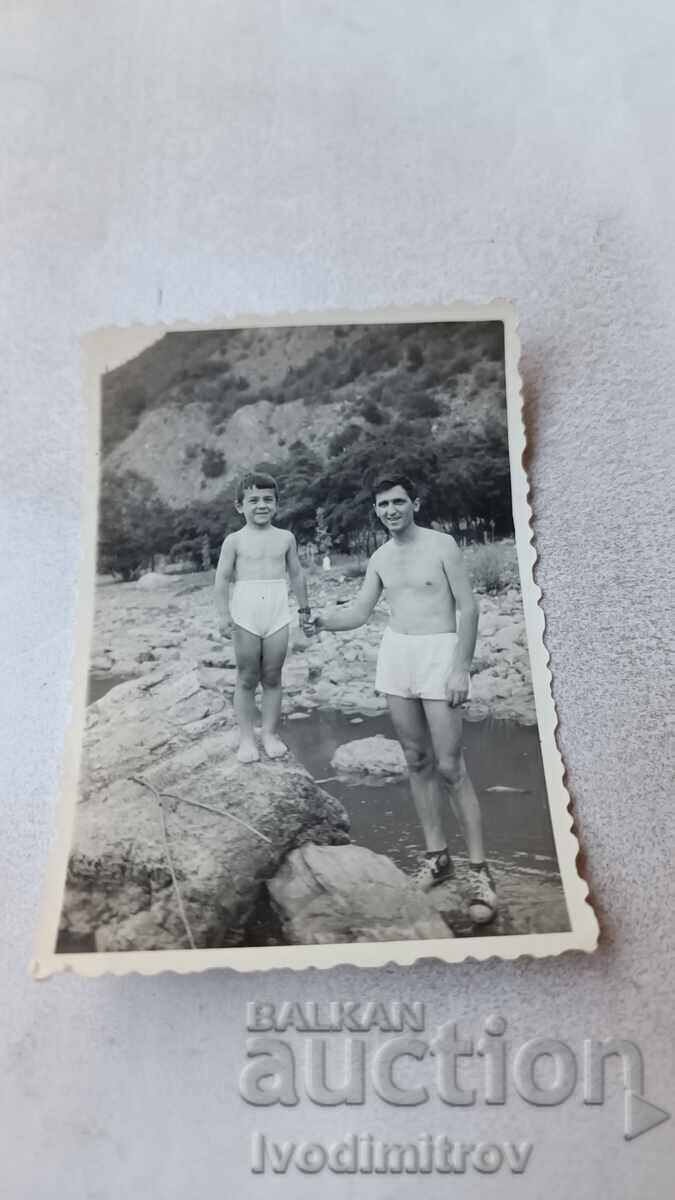 Photo Man and boy in shorts on rocks