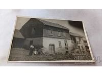 Photo Man, woman and two children in front of a country house