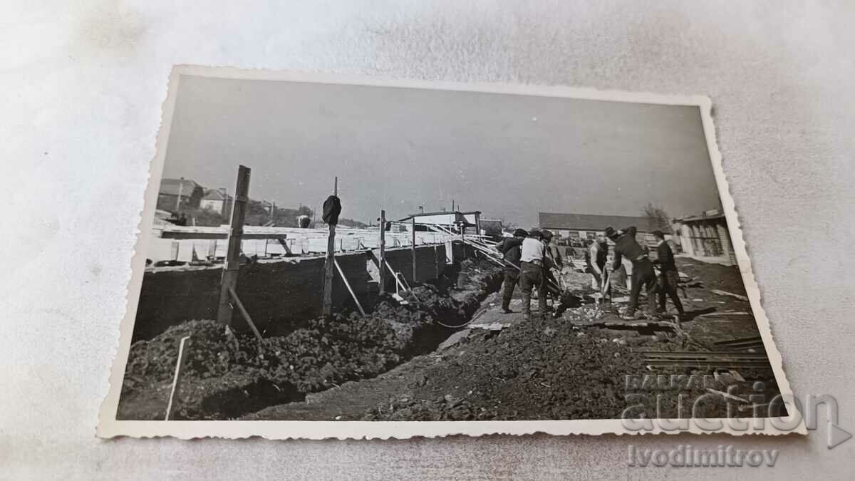 Imagine Constructorii lângă fundațiile unui șantier