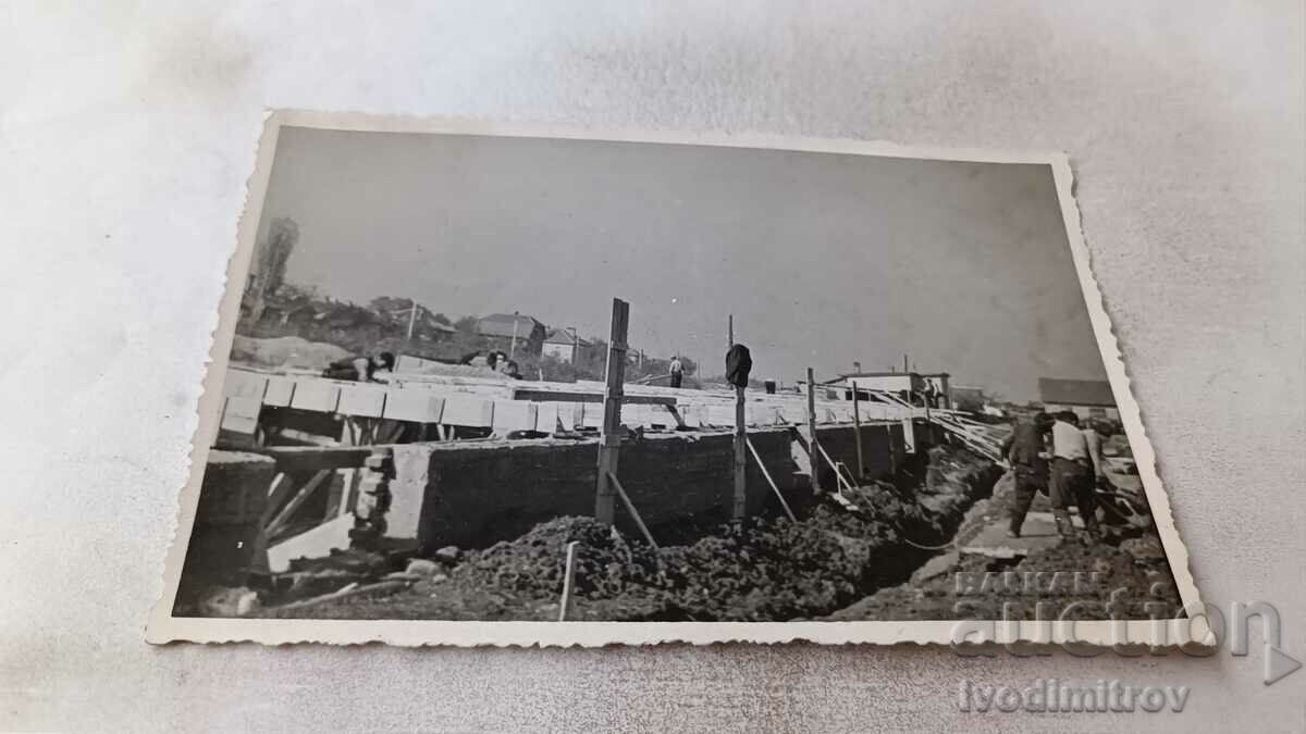 Imagine Constructorii lângă fundațiile unui șantier