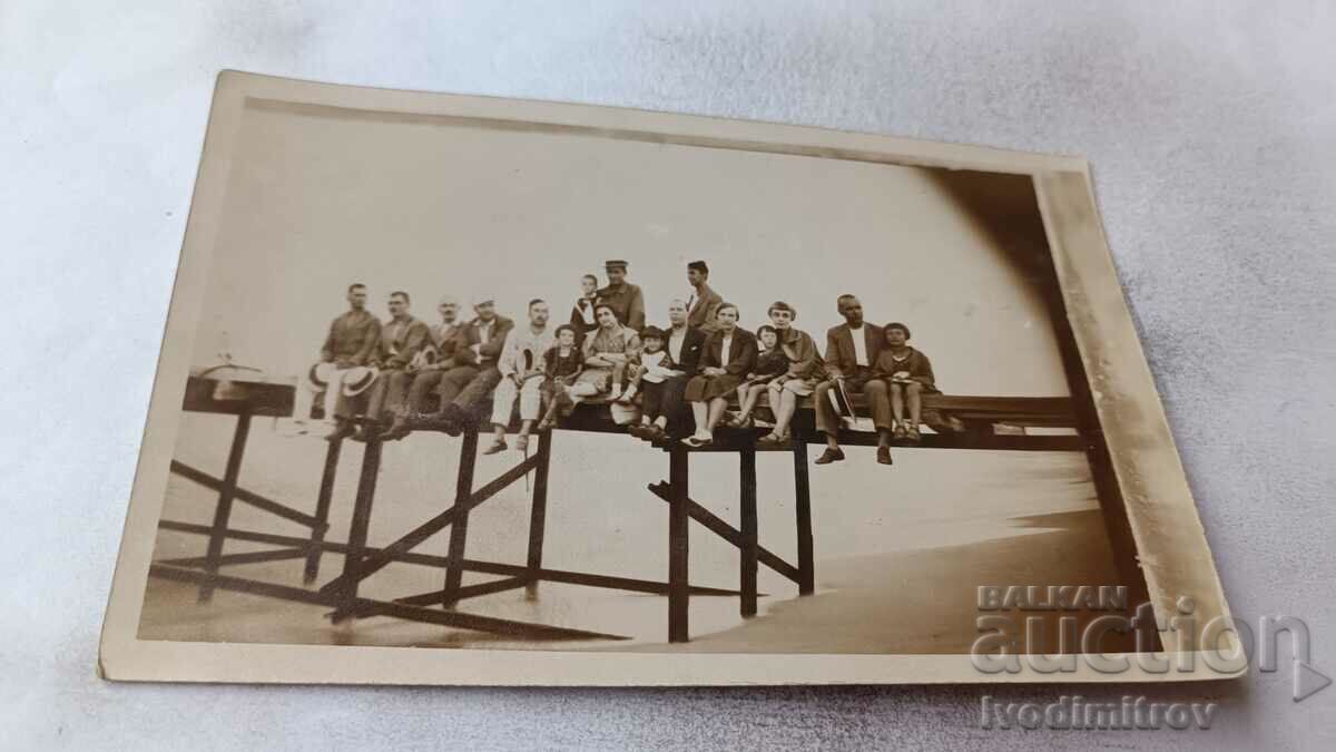 Photo Men, women and children sitting on the pier