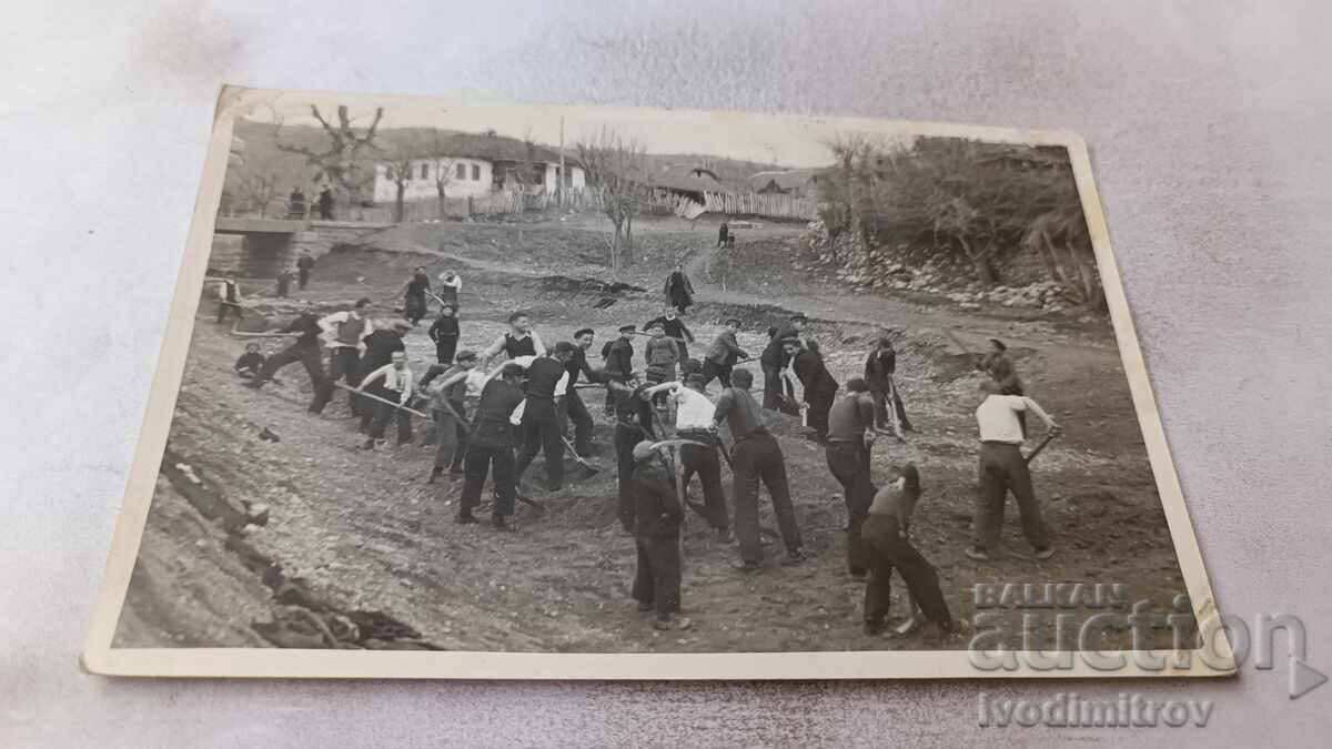 Photo Young people with picks and shovels in the ravine of a river