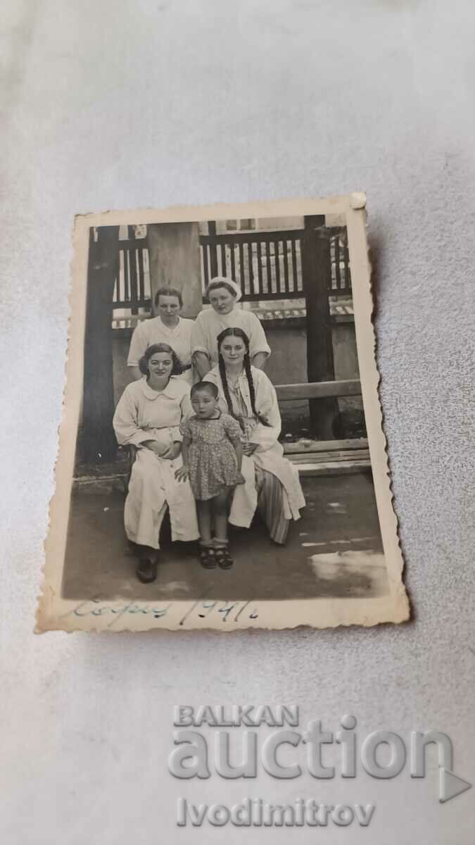Σ. Σοφία Τέσσερις νεαρές γυναίκες με άσπρες ποδιές και ένα κορίτσι σε ένα παγκάκι
