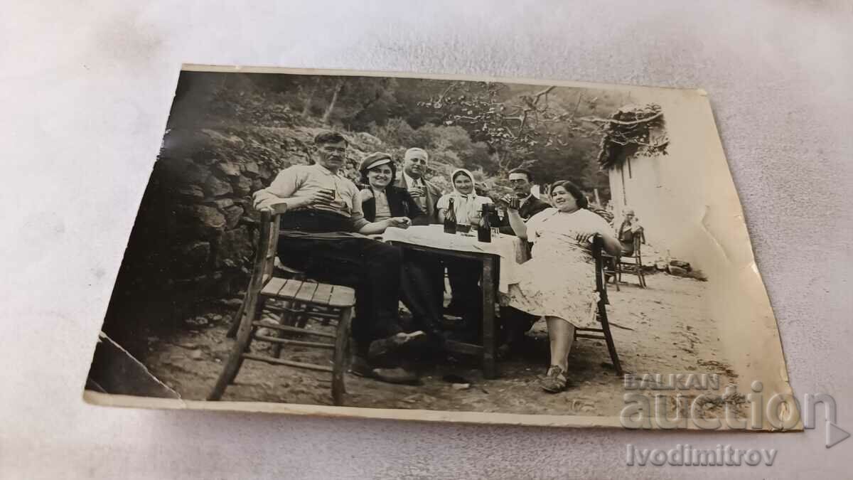 Imagine Bărbați și femei care beau la o masă