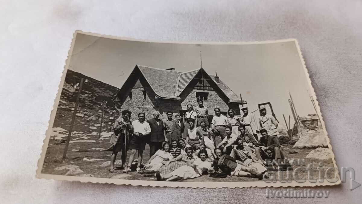 Fotografie Bărbați și femei în fața unei cabane de munte