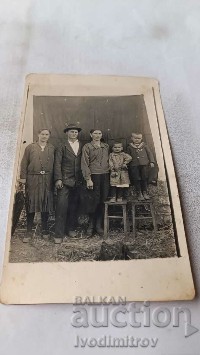 Εικόνα Άνδρας δύο γυναίκες και δύο παιδιά σε μια ξύλινη καρέκλα