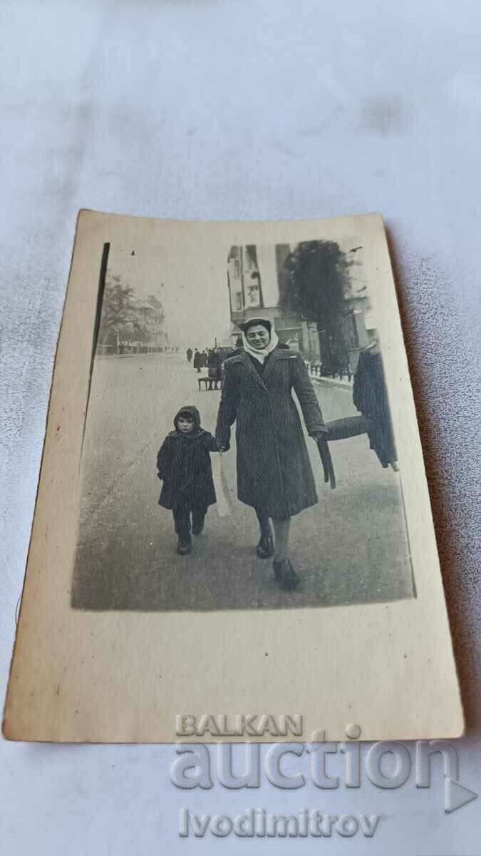 S. Sofia A little girl and a woman carrying a stool on the sidewalk