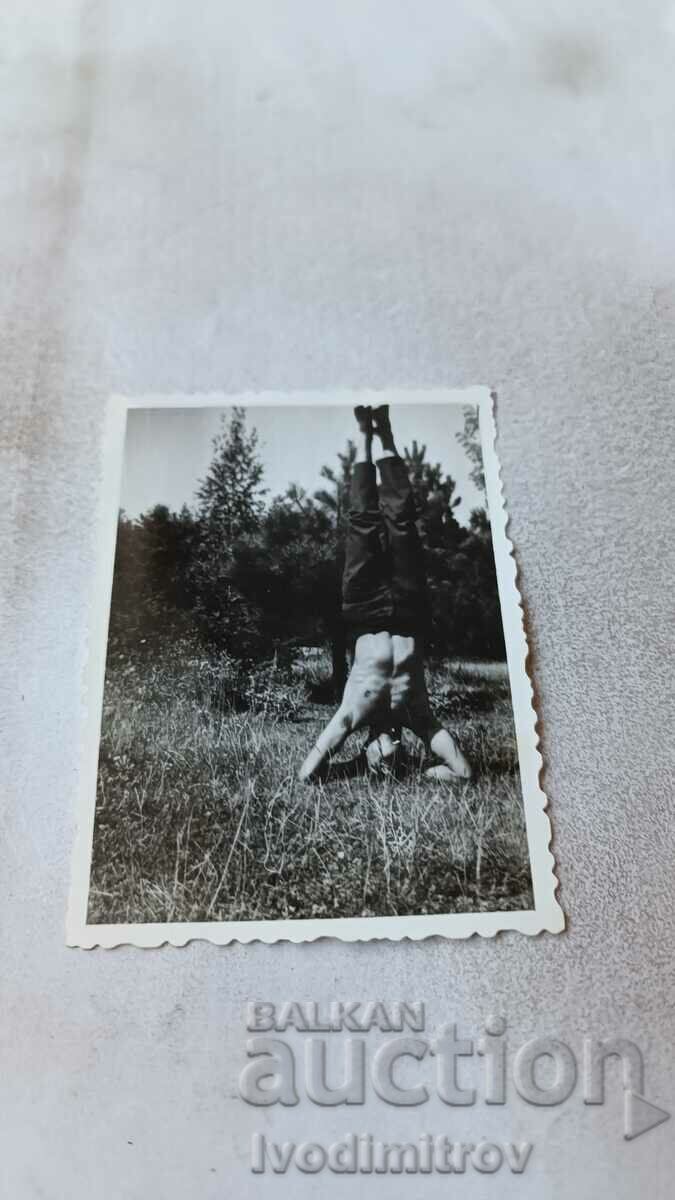 Photo Young man naked to the waist in a headstand