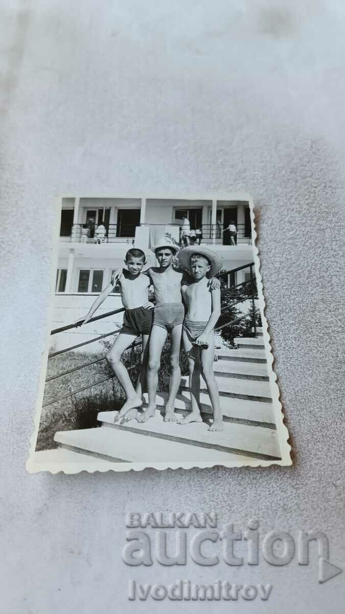 Photo Three boys in swimsuits on the stairs