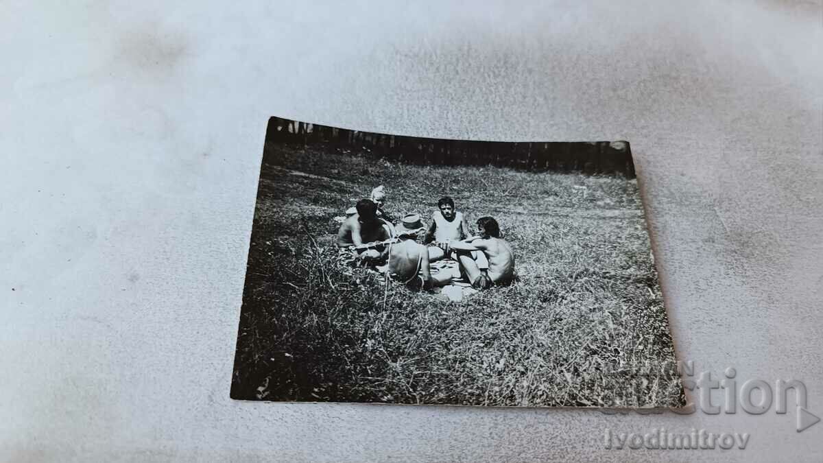 Photo Four young men playing cards on the grass