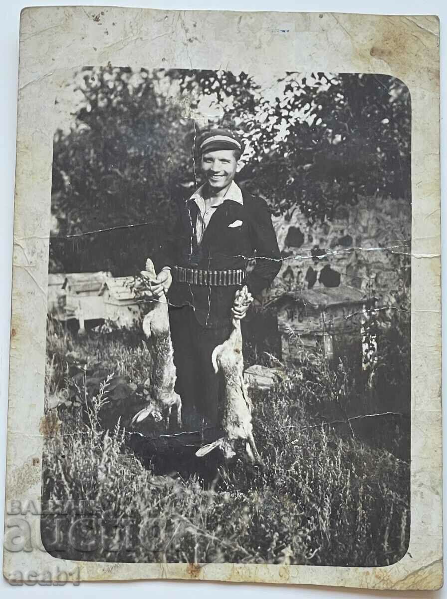 A hunter with a catch of two rabbits