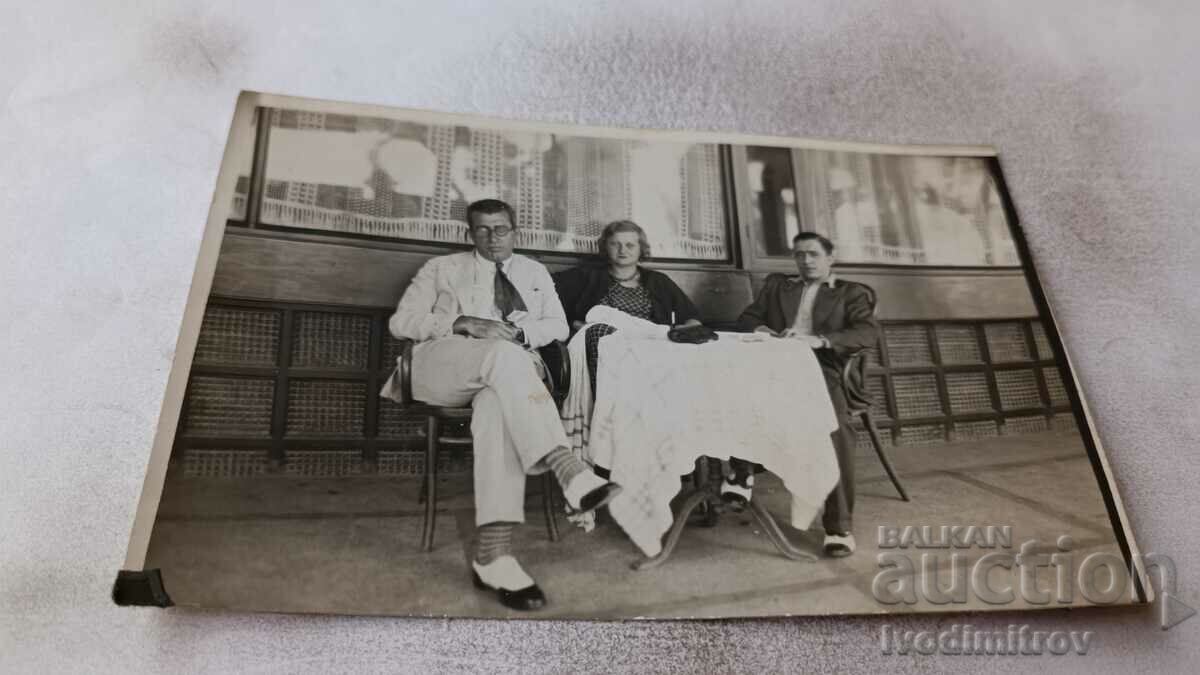 Снимка Двама мъже и млада жена на маса