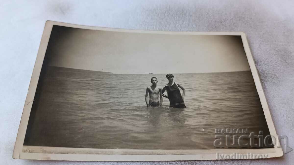 Photo A young man and a young girl in a vintage swimsuit in the sea