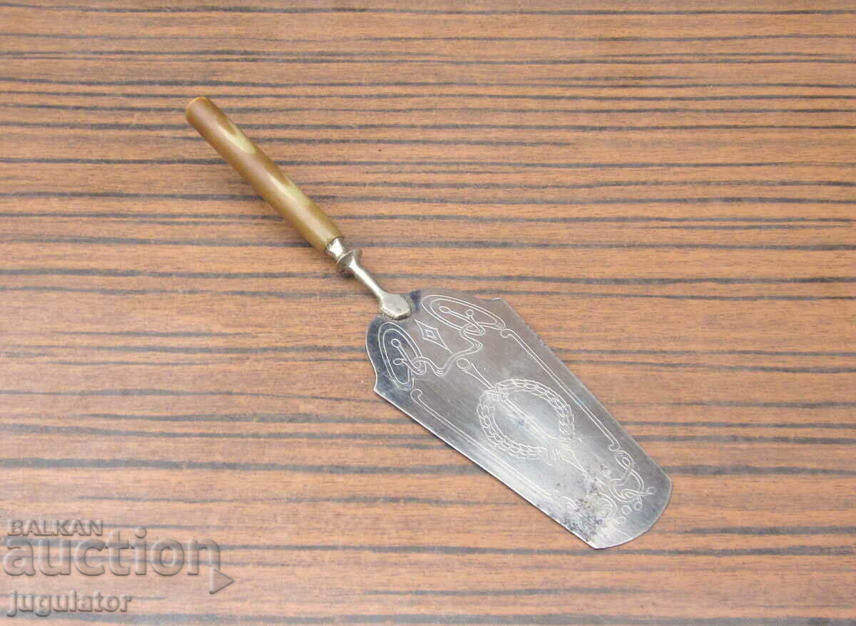 an old serving spatula with ornaments and bakelite handle