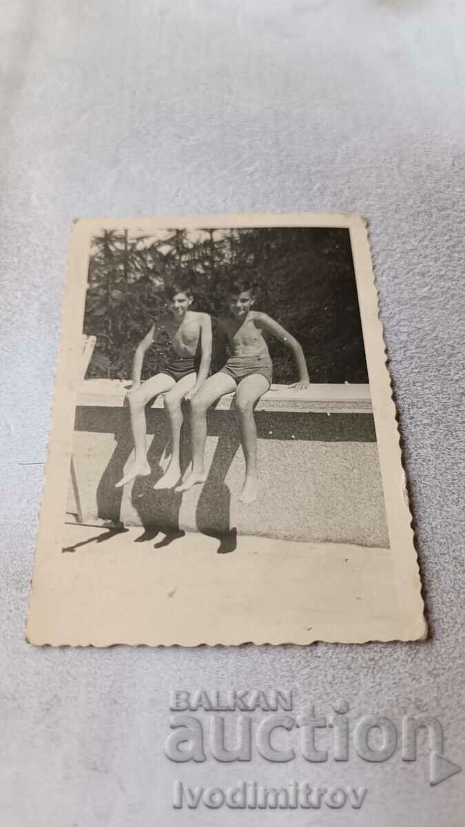 Photo Two boys in swimsuits sitting on a ledge 1943