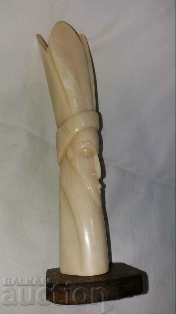 An old figure sculpts a white bone totem An old figure sculpts a white bone totem