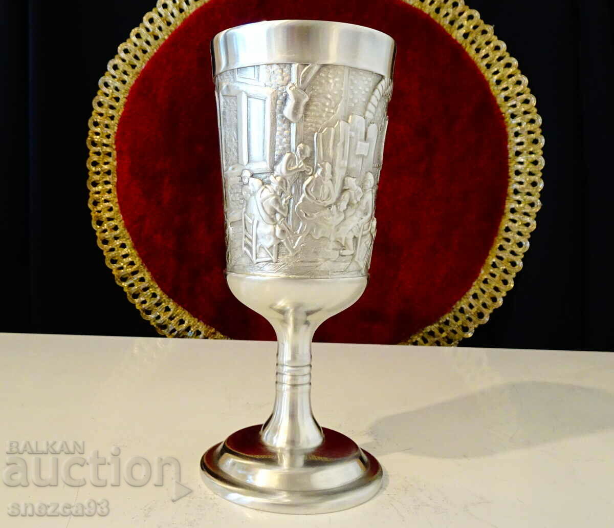A pewter wine glass with an embossed pub picture.
