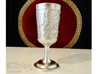 A pewter wine glass with an embossed pub picture.