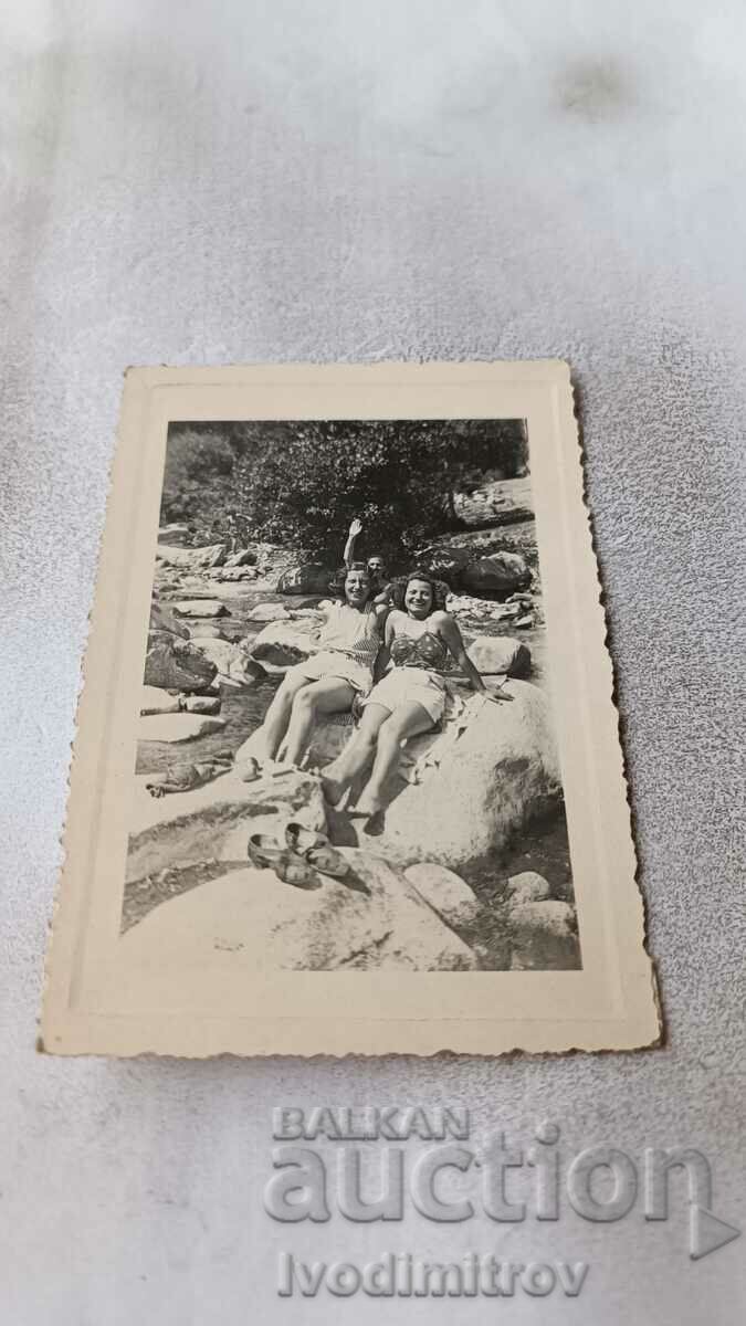 Photo A man and two young girls on a stone in a river bed