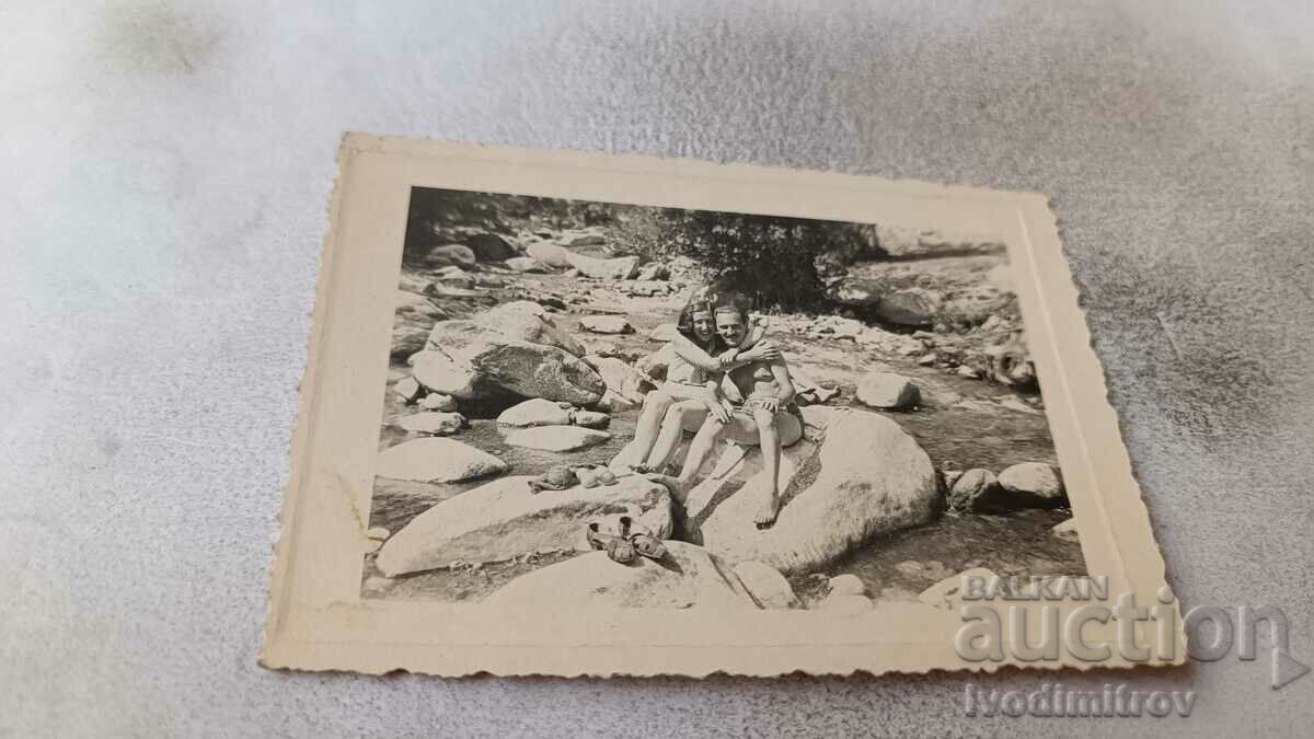 Снимка Мъж младо момиче на камък в коритото на река