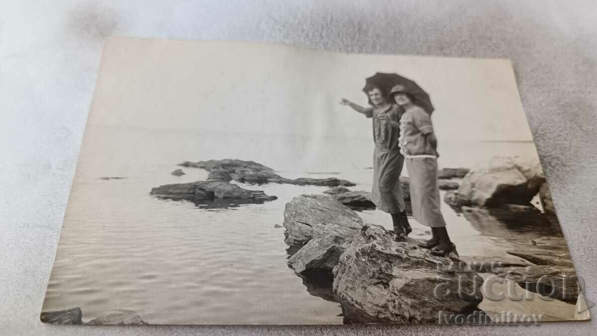 Fotografie Două tinere pe o piatră lângă mare