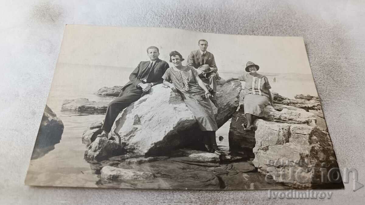 Photo Two young women and two young men on rocks by the sea