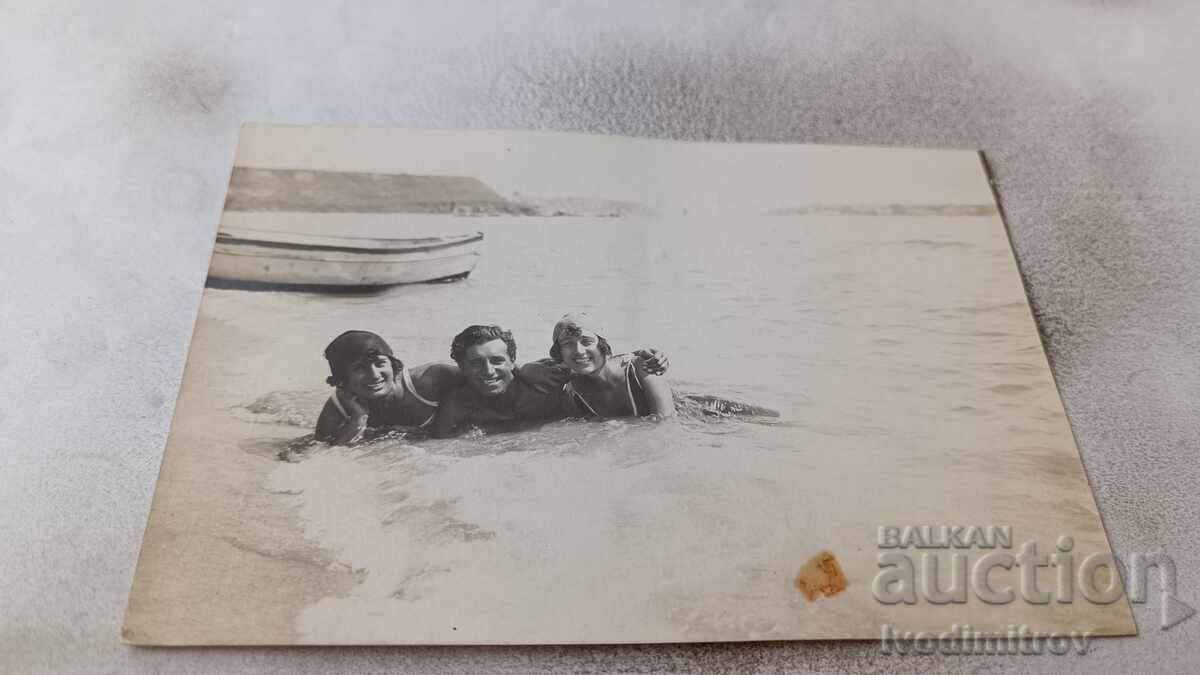 Photo A young man and two girls on the beach