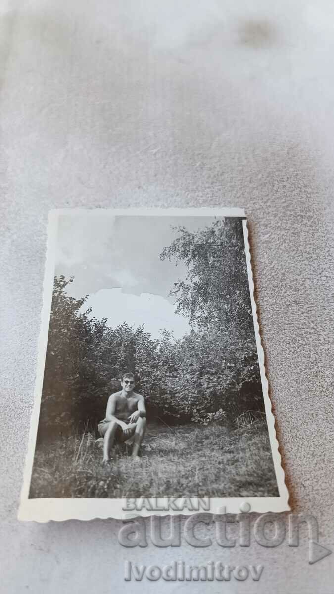 Photo A man in shorts sitting on the grass