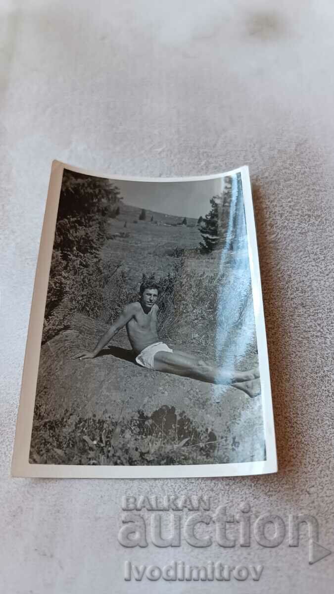 Снимка Мъж по бански седнал на скала