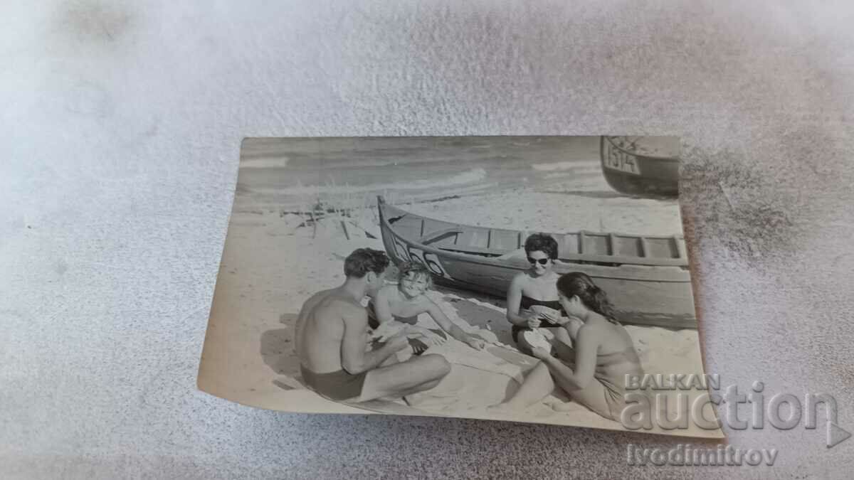 Εικόνα Ένας άντρας και τρεις γυναίκες παίζουν χαρτιά στην παραλία