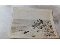 Φωτογραφία Νεαροί άνδρες και γυναίκες σε βράχια δίπλα στη θάλασσα