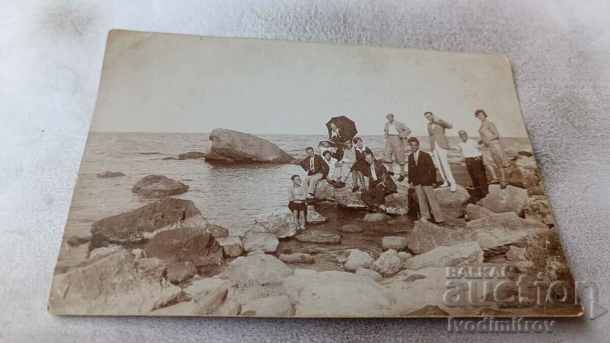 Photo Men women and boy on rocks by the sea
