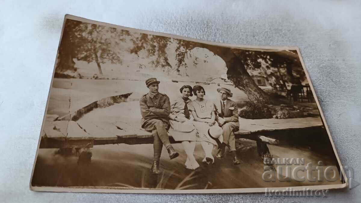 Φωτογραφία Ένας άνδρας αξιωματικός και δύο νεαρές γυναίκες κάθονται σε μια γέφυρα