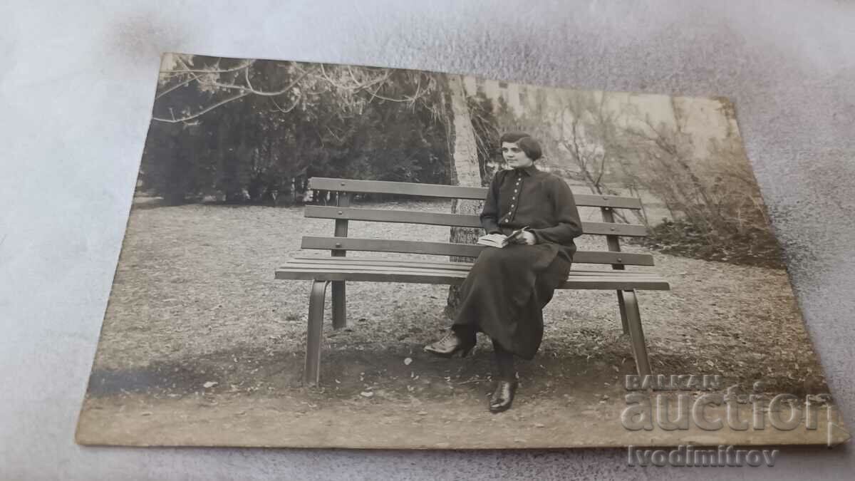 Φωτογραφία Νεαρό κορίτσι που κάθεται σε έναν ξύλινο πάγκο στο πάρκο 1924