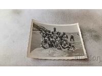 Foto Bărbat și fete tinere în costume de baie pe plajă
