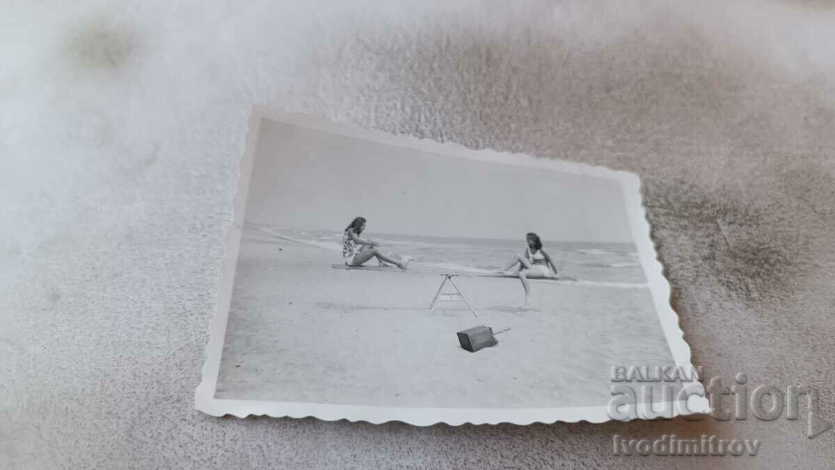 Photo Two young girls wooden swing on the beach
