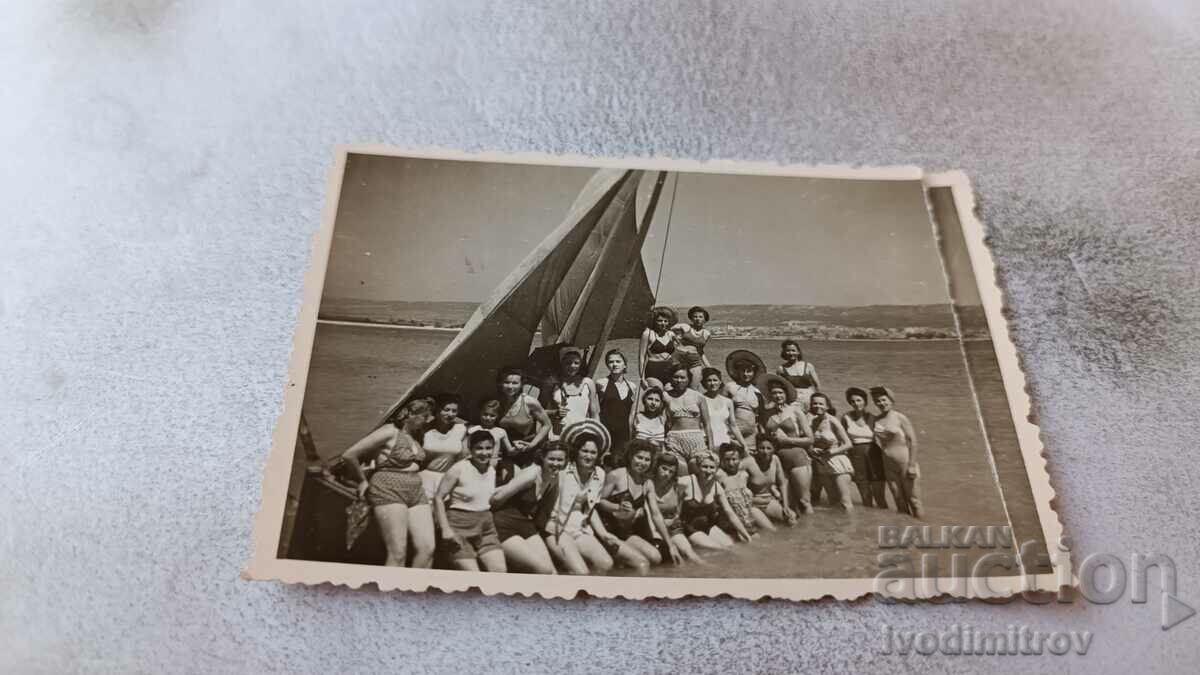 Foto Femei și fete în fața unei bărci cu pânze în mare