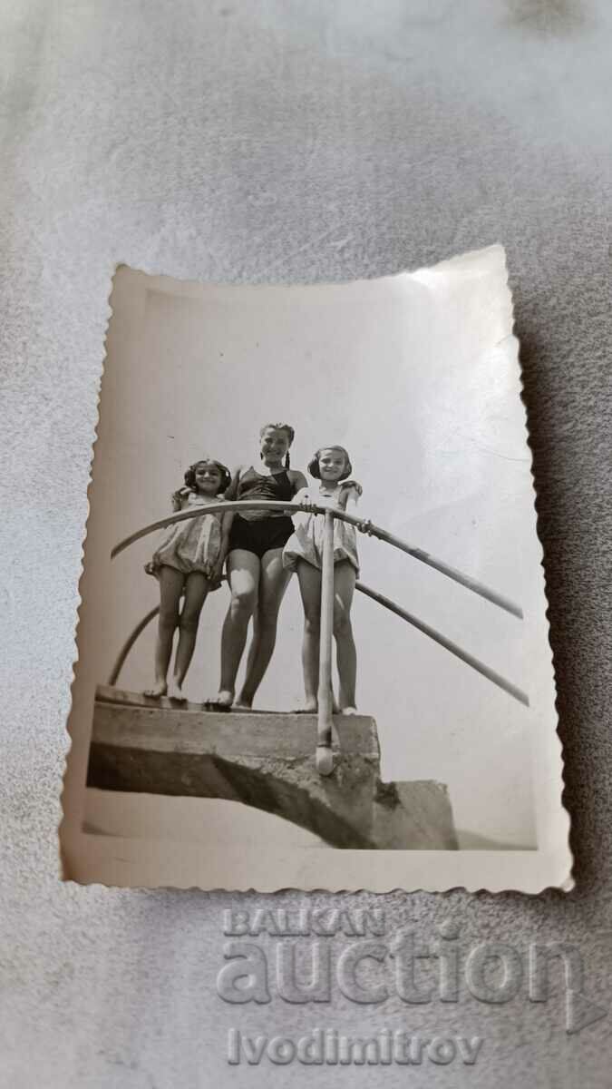 Photo Three girls in swimsuits on a pool ladder