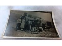 Photo Men, women and a dog in front of a steam locomotive