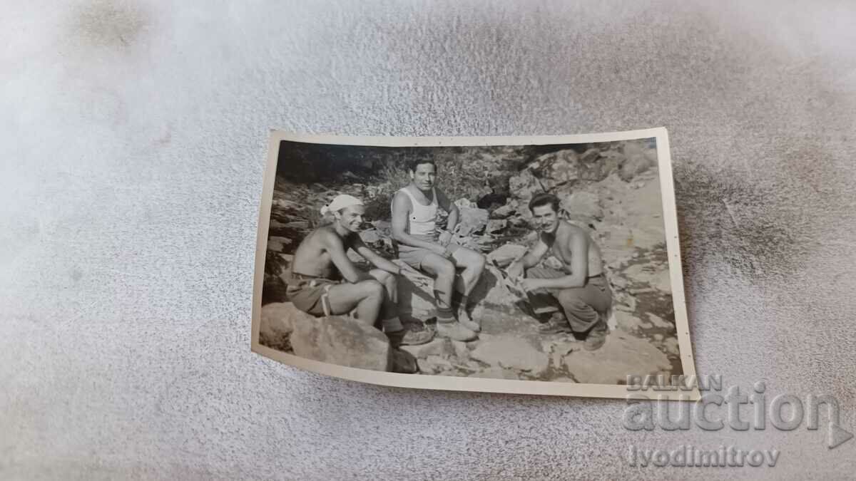 Photo Three men in shorts on the rocks