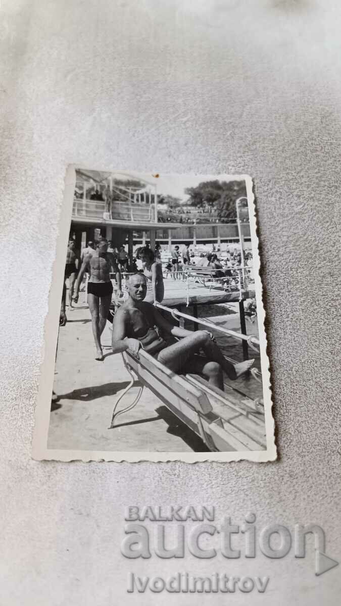 Photo A man in a swimsuit sitting on a bench on the pier